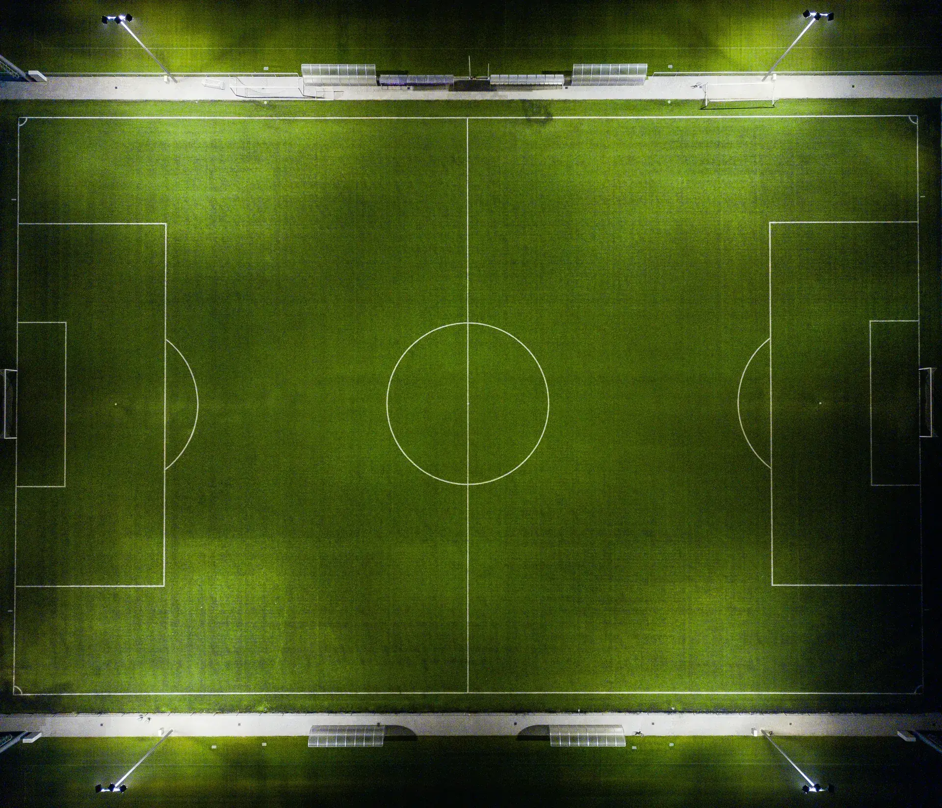 Widok z góry na oświetlone boisko piłkarskie ze sztuczną nawierzchnią w nocy